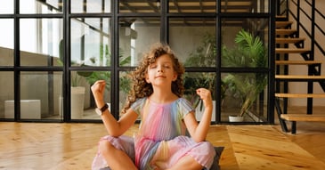 young girl in rainbow dress in lotus pose