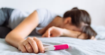 sad woman struggling with infertility holding negative pregnancy test 