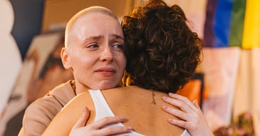 tearful young woman hugging an older woman