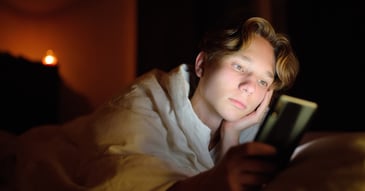 sad teen up late scrolling social media on phone