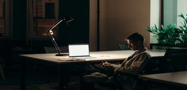 person sitting at desk with computer and task lamp