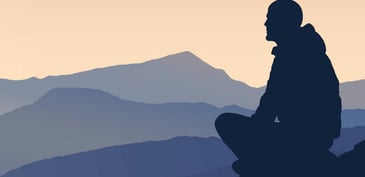 figure meditating at sunset in a mountain range
