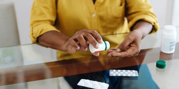 managing medication for mental health with focus on pill bottle and organizer in hands