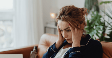 Woman in bathrobe pulling hair while looking at her device