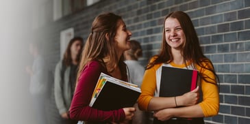 Nervous teen girls preparing to enter high school with new notebooks