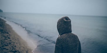 A hooded man watching the sea