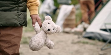 child's hand holding teddy bear during trips to mom's house, dad's house