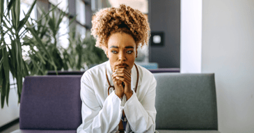 female healthcare worker in white coat and stethescope suffering from fatigue