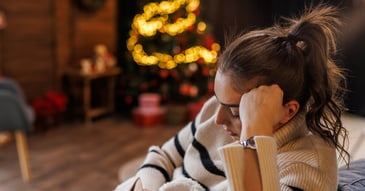 Sad, grieving woman near Christmas tree