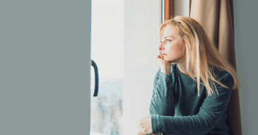 anxious depressed woman looking out window and thinking