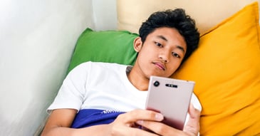gloomy adolescent scrolling through social media on phone