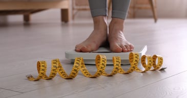 feet weighing thin lady on scale with spiral of measuring tape