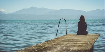 Woman sitting on a dock. Photo by <a href=
