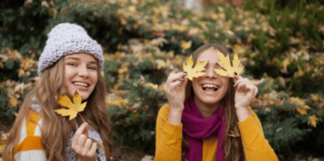 tween girls playing with fall leaves in group